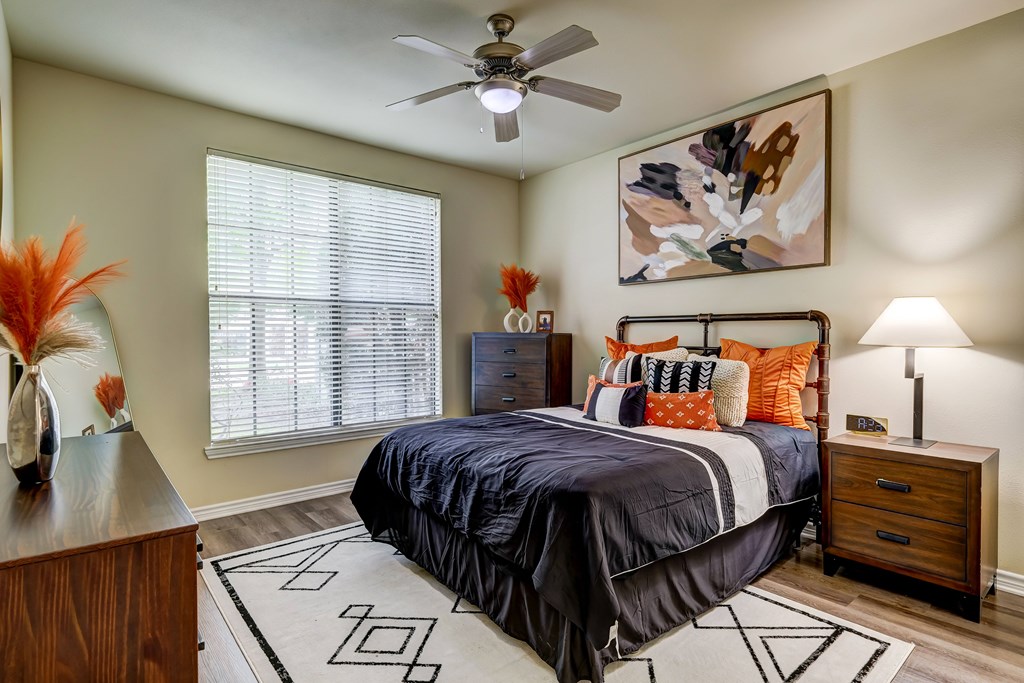 A bedroom with a bed, nightstand, and a painting on the wall.